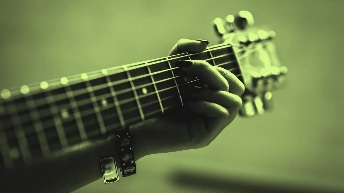 Fingers forming a chord on a fretboard.
